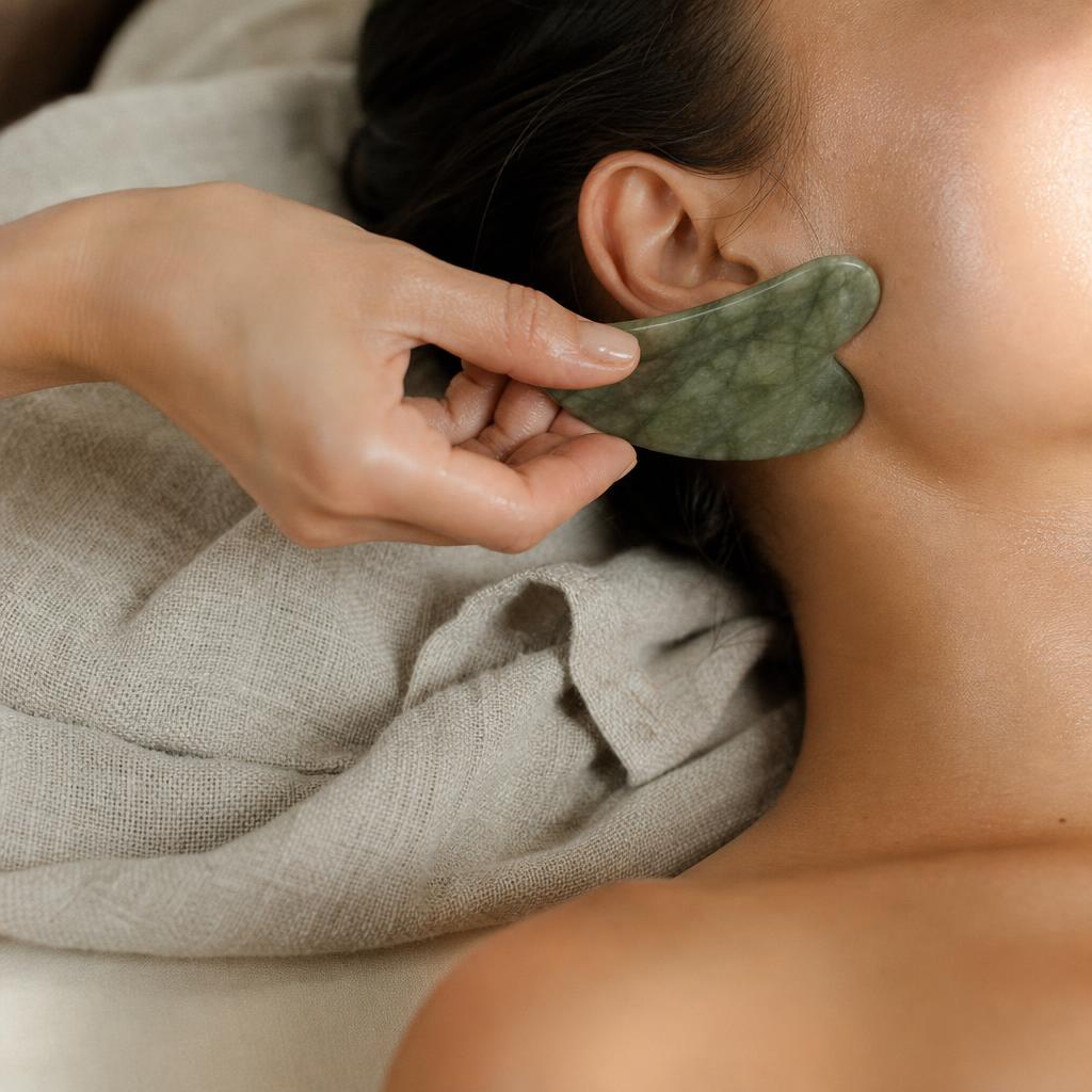Gua sha en jade glissé le long de la mâchoire pendant un massage du visage